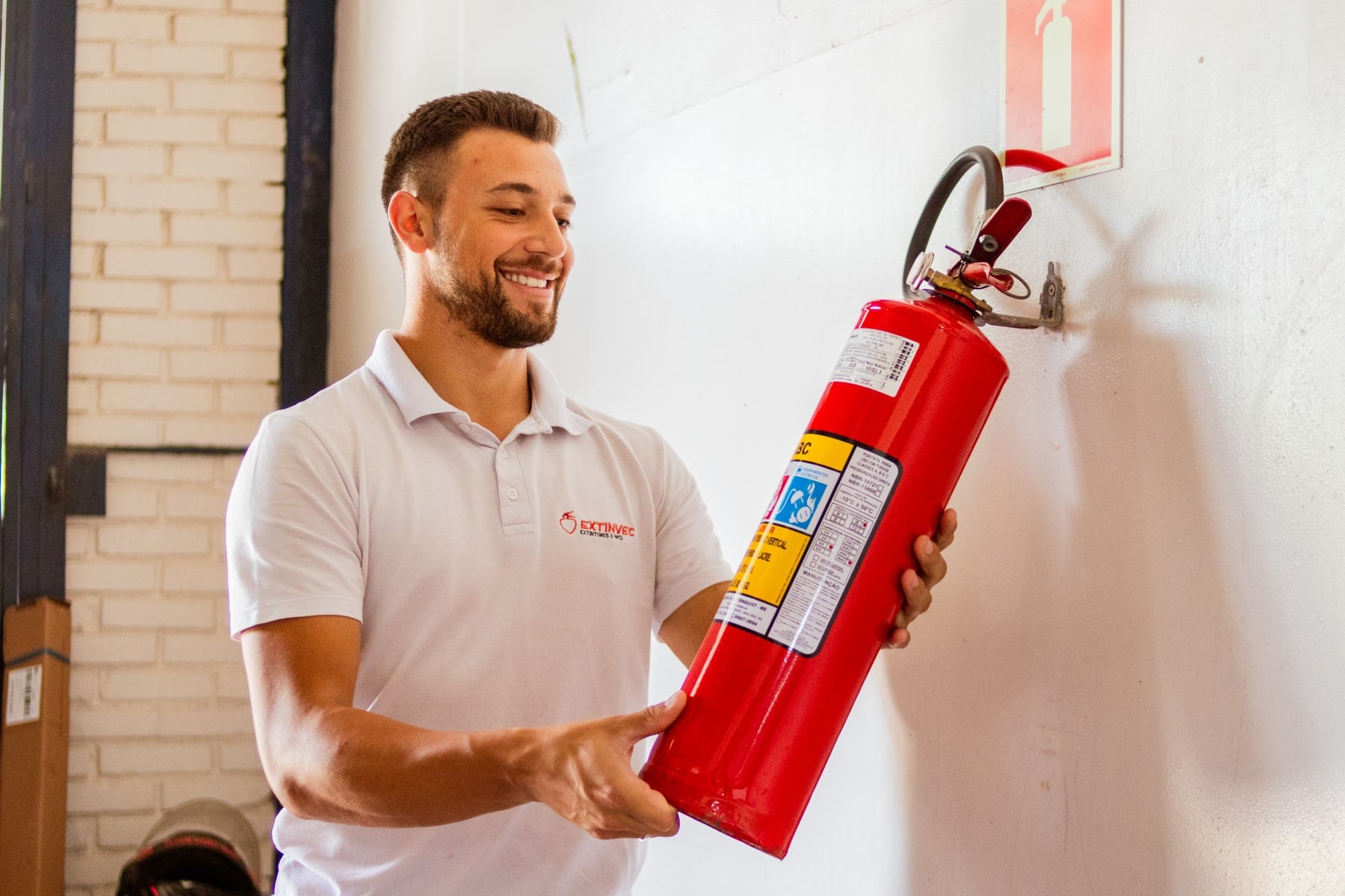 Técnico da Extinvec instalando um extintor de pó ABC